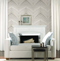 White sofa positioned in front of a fireplace with Candice Olson Onyx Strata Wallpaper by York Wallcoverings in the background.
