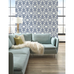 Large Lattice Wallpaper by York Wallcoverings with a blue geometric lattice pattern of interlocking ovals and rectangles, installed on a wall behind a light blue sectional sofa.