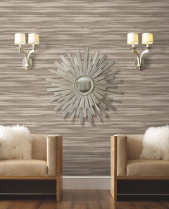 Two armchairs with fuzzy white pillows sit against a wall covered in Candice Olson Sanctuary Wallpaper, accented by a sunburst mirror and two wall sconces.