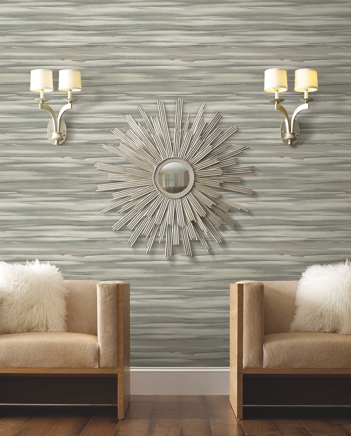 Candice Olson Sanctuary Wallpaper featuring a horizontal, brushstroke-style pattern in shades of gray, white, and blue, displayed behind two tan chairs and a sunburst mirror.