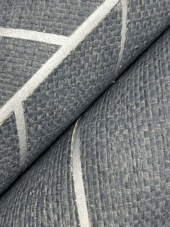 Close-up of two rolls of Ronald Redding Atelier Herringbone Wallpaper by York Wallcoverings, featuring a textured gray surface with a woven pattern and thin, shiny, light-colored diagonal lines.