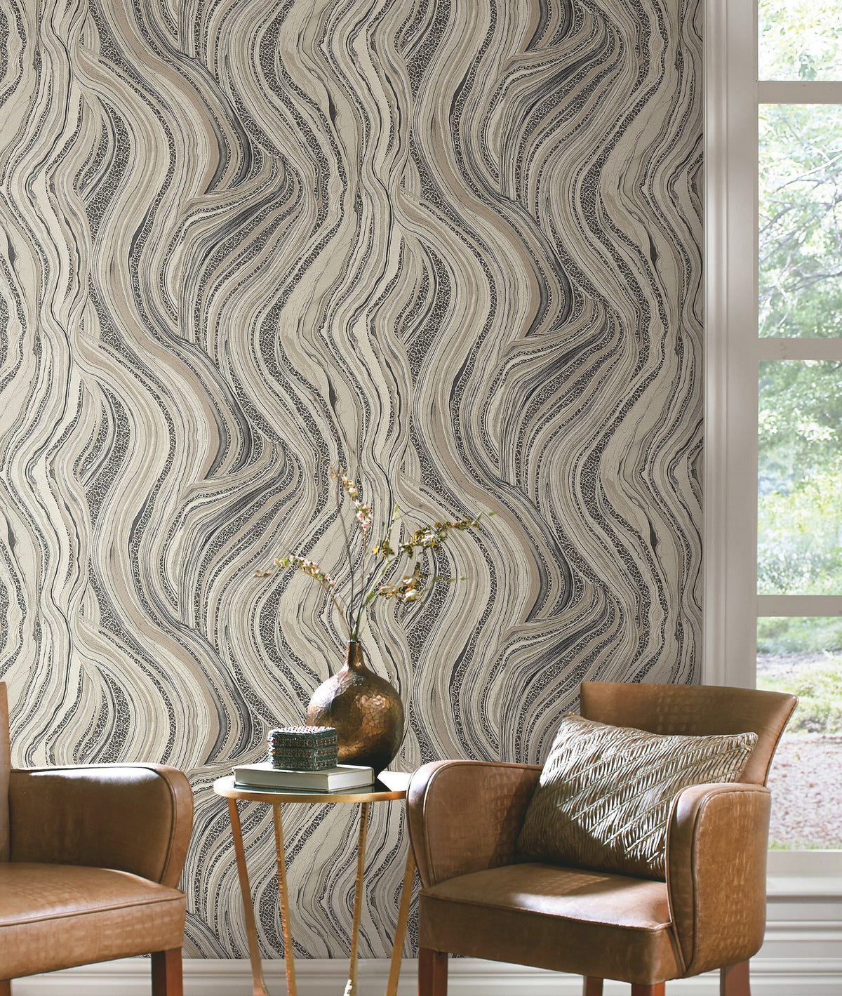 Ronald Redding Streaming Cheetah Wallpaper with a swirling, abstract pattern of black, white, and tan lines on a wall behind two leather armchairs and a small side table.