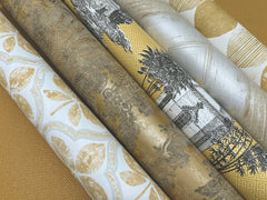 Five rolls of Ronald Redding Charleston Damask Wallpaper featuring gold, white, and black patterns, including floral motifs, palm trees, and geometric prints.