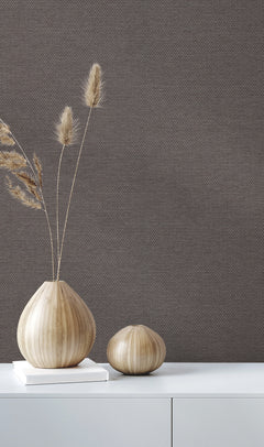 Two wooden vases with dried grass on a white surface are set against a backdrop of QuietWall Varna Wallpaper by York Wallcoverings, creating a minimalist and natural decor setting.