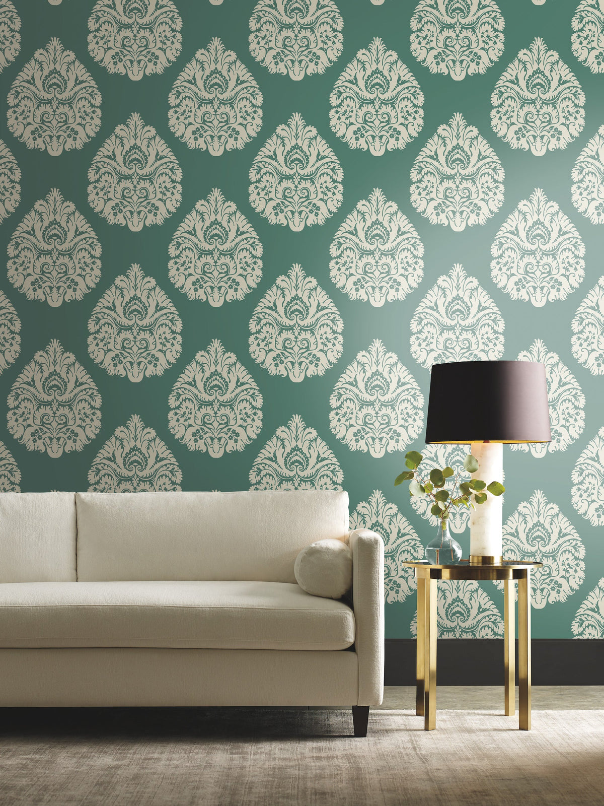 Ronald Redding Teardrop Damask Wallpaper featuring a repeating white teardrop-shaped pattern on a dark green background, displayed behind a white sofa and a side table with a lamp.