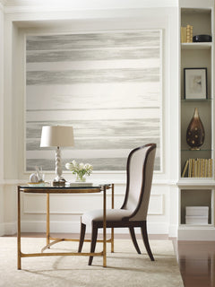 Ronald Redding Horizontal Dry Brush Wallpaper by York Wallcoverings featuring soft, horizontal grey and white stripes with a textured, dry-brush effect installed on an accent wall behind a writing desk.