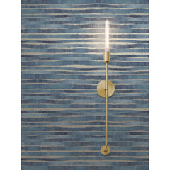 A gold-toned wall sconce with a long, exposed filament bulb mounted on blue, horizontally striped Ronald Redding Dreamscapes Wallpaper by York Wallcoverings.