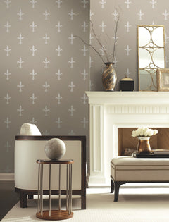 Taupe Ronald Redding Fleur De Lis Wallpaper with a repeating white fleur-de-lis pattern installed in a living room featuring a white fireplace.