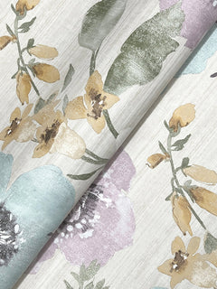York Wallcoverings’ Evelyn Floral Wallpaper features a repeating botanical design with yellow, green, and purple flowers and leaves set against a light, textured background. The wallpaper is shown folded to highlight its elegant floral pattern.