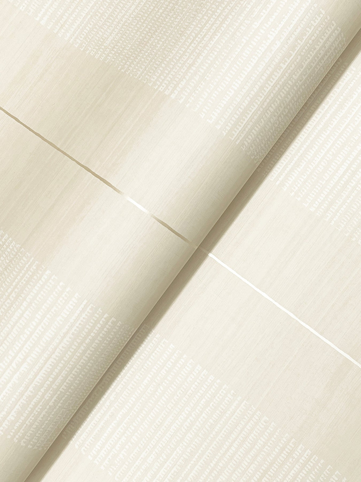 A close-up of Colbert Stripe Textured Wallpaper in light beige features subtle horizontal and vertical textured lines that create a grid-like pattern with a soft sheen; the wallpaper is shown slightly folded.
