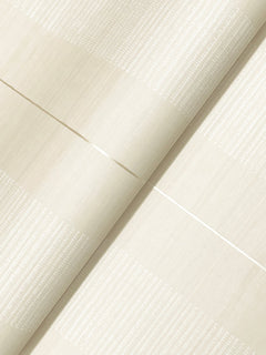 A close-up of Colbert Stripe Textured Wallpaper in light beige features subtle horizontal and vertical textured lines that create a grid-like pattern with a soft sheen; the wallpaper is shown slightly folded.