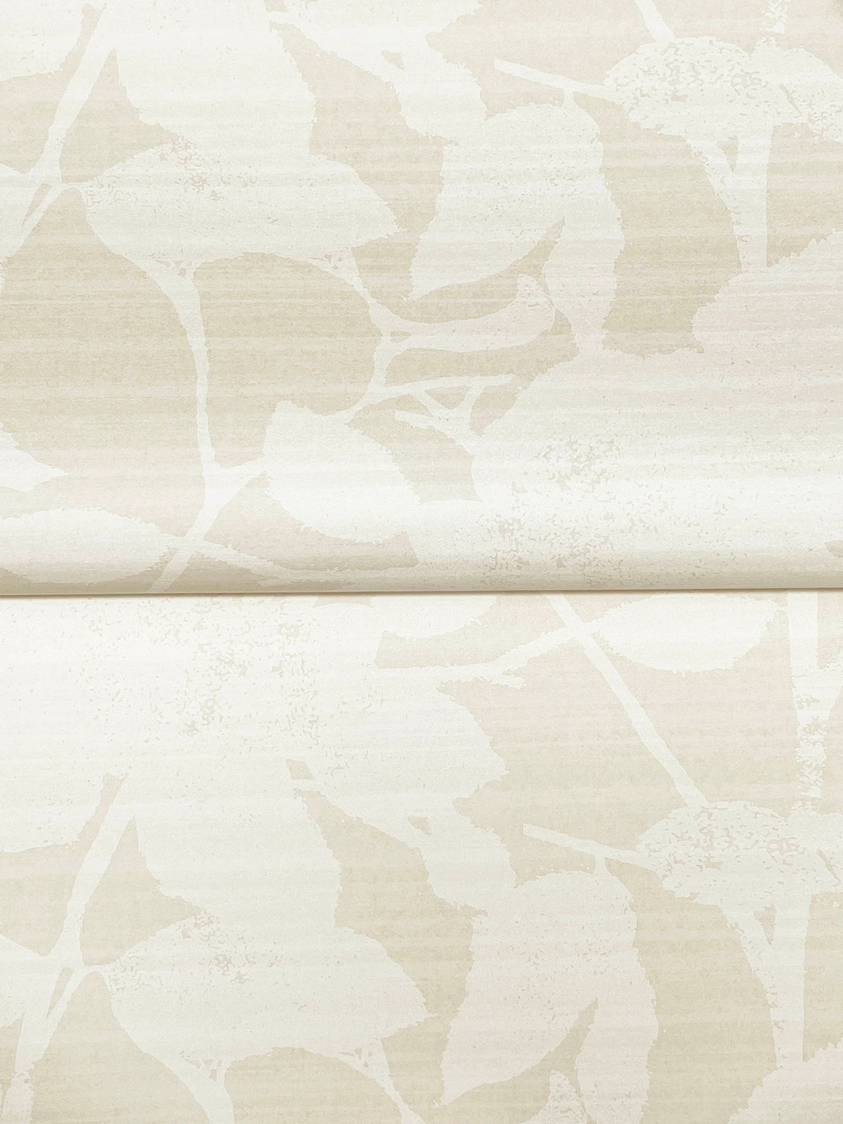 The Solange Botanical Wallpaper by York Wallcoverings features a beige background adorned with a subtle, abstract leaf pattern. In the image, a horizontal seam is visible where two sections of the wallpaper meet, and the light leaves blend softly into the background for an understated look.