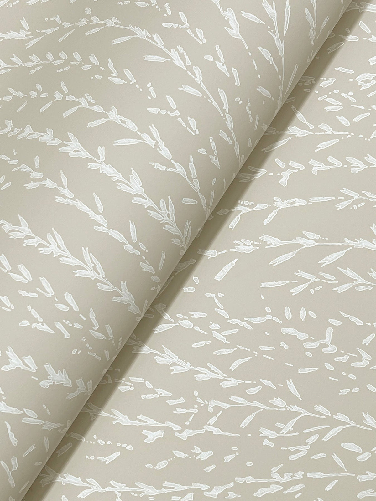 Experience the Willow Song Botanical Wallpaper by York Wallcoverings—beige paper adorned with a subtle white pattern of delicate leaves and branches, partially rolled to showcase its texture and refined design.