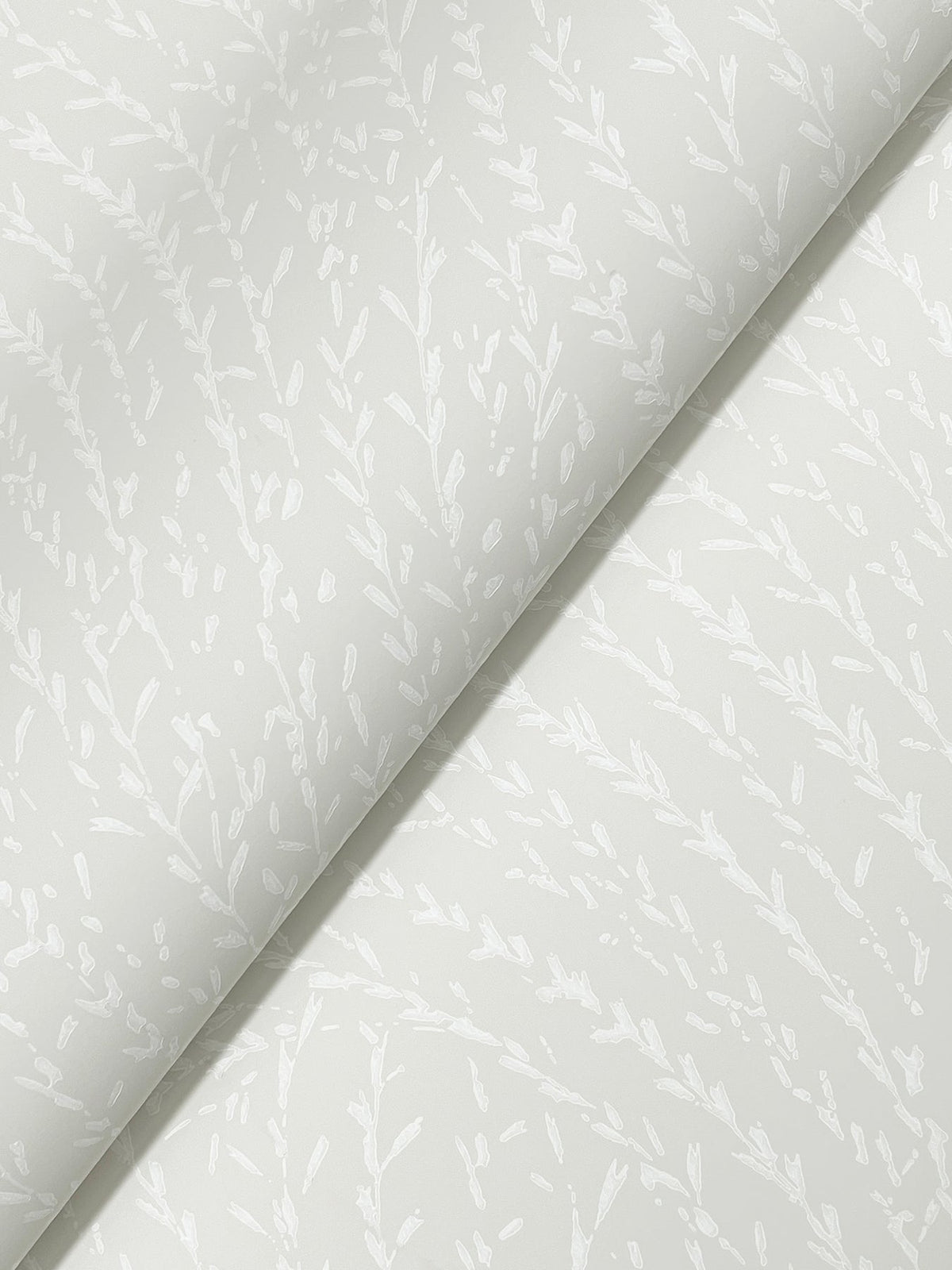 Two sheets of York Wallcoverings’ Willow Song Botanical Wallpaper in pale gray, featuring a subtle white leafy branch motif, overlap diagonally. The minimal botanical design offers a soft and elegant look, making it perfect for decorative accents or wrapping applications.