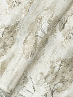 York Wallcoverings’ Moreno Woodland Wallpaper features a painterly, nature-inspired pattern of trees and foliage in soft beige and light brown tones. The wallpaper is shown with gentle folds, highlighting its texture and intricate design details.