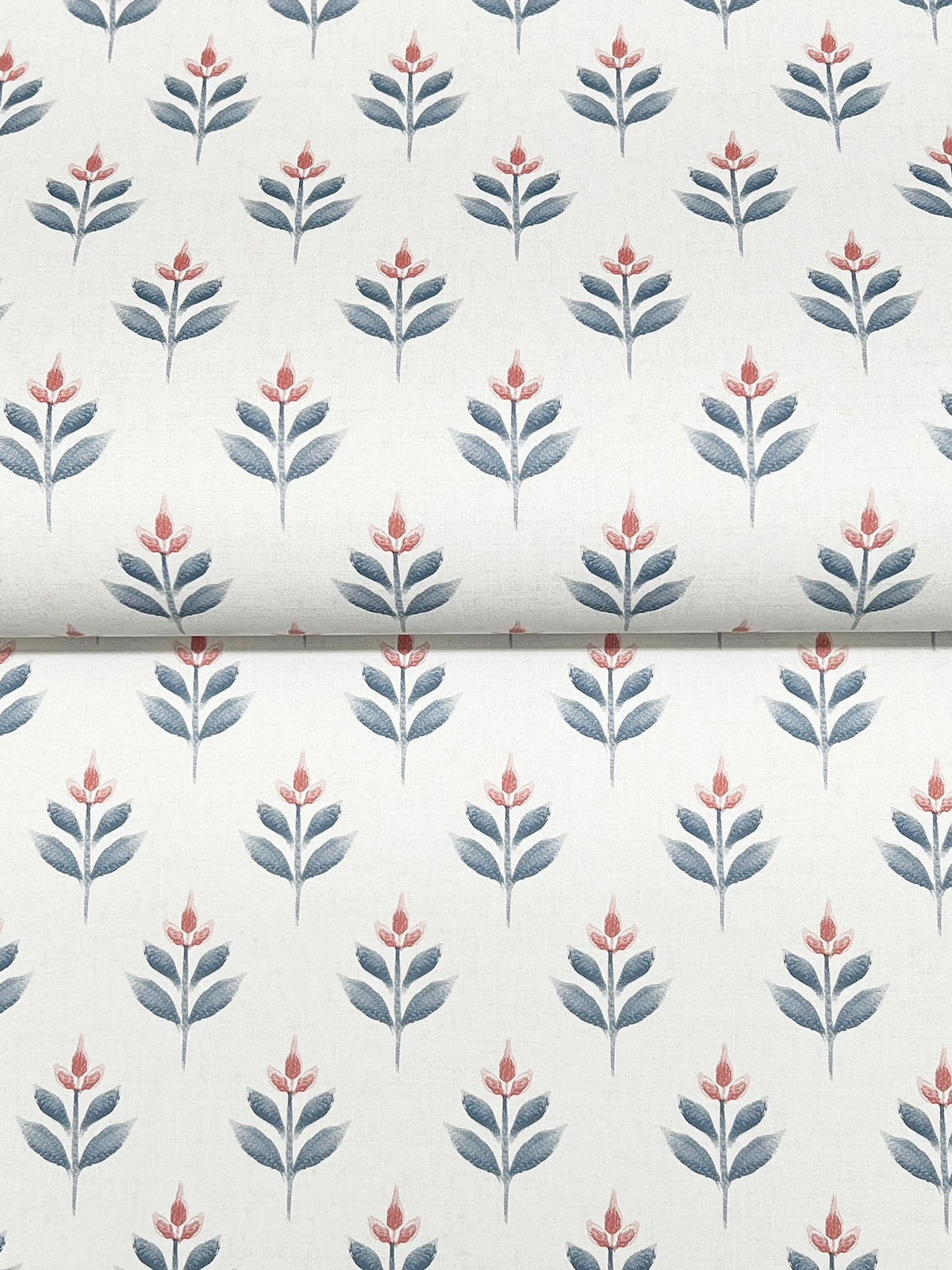 Serene Villa Floral Stamp Wallpaper by York Wallcoverings features a pattern of stylized flowers—each with blue leaves and a red-pink blossom—arranged in neat rows on a white background. The wallpaper is shown folded horizontally across the middle.