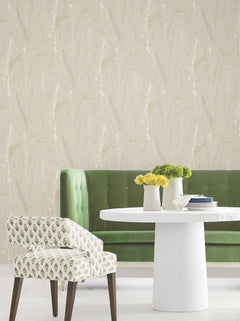 A green tufted bench, a round white table with yellow flowers, and a patterned chair sit against the Meadow Splendor Botanical Wallpaper.