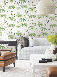 Bright living room featuring a light blue sofa, brown leather chairs, and a white coffee table against Cillian Botanical Bird Trail Wallpaper by York Wallcoverings. Decorative pillows, green-yellow flowers, and a modern white lamp complete the stylish and inviting space.