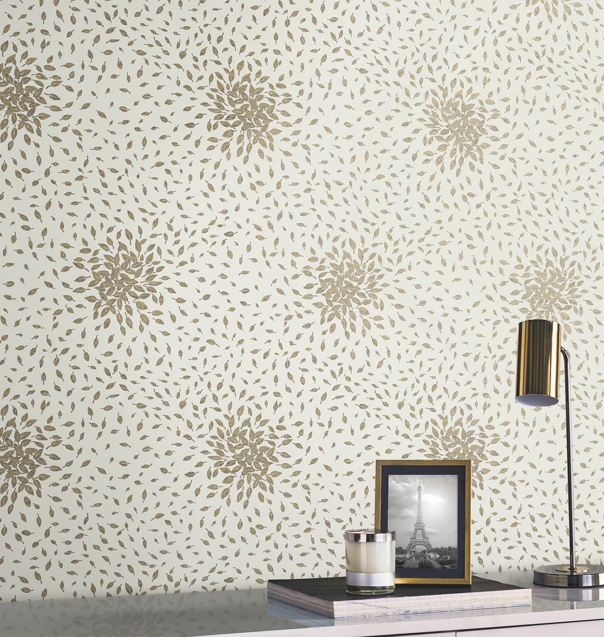 A Petite Leaves Wallpaper by York Wallcoverings with gold floral patterns, a modern desk lamp, and a framed black-and-white photo of the Eiffel Tower placed on a sleek, reflective surface.