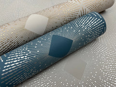 Two rolls of Harlowe Wallpaper by York Wallcoverings—one in teal with silver lines and the other in beige with gold lines—each featuring a geometric sunburst pattern centered around a diamond shape.
