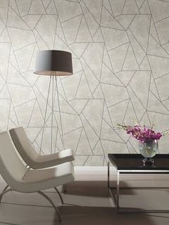 Two modern white chairs, a tall floor lamp, and a black coffee table with a vase of purple flowers sit in front of Nazca Wallpaper by York Wallcoverings in a minimalist room.