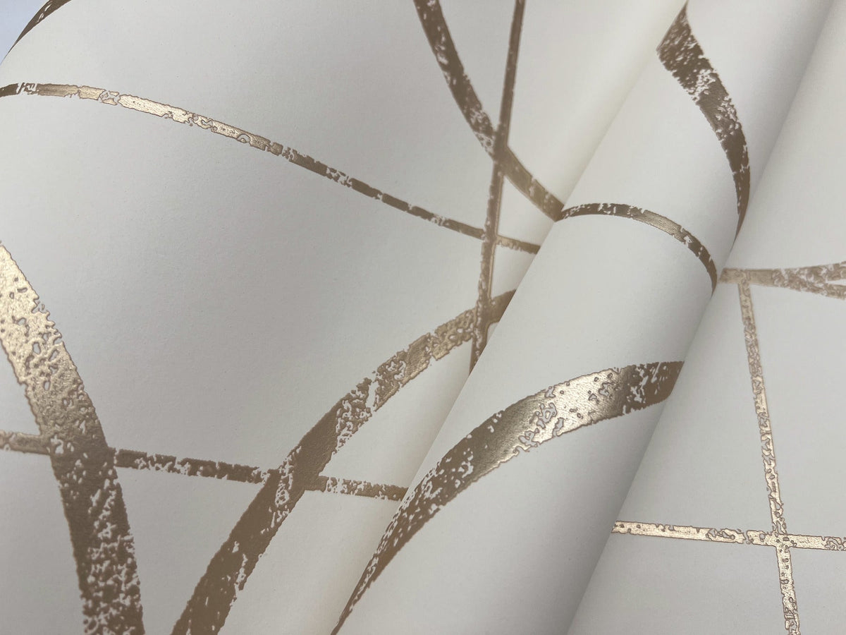 Close-up of Sun Circles Wallpaper by York Wallcoverings, featuring cream-colored paper with metallic gold geometric lines and curves that create a modern abstract pattern. The slightly textured, reflective gold lines add dimension to the design.