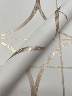 A close-up of the Sun Circles Wallpaper by York Wallcoverings, showcasing its metallic gold geometric pattern with intersecting lines and curved shapes on a crisp white background.