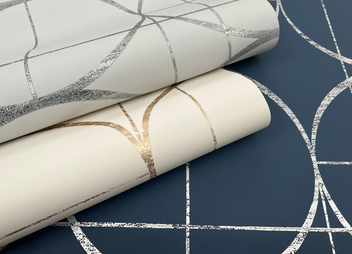 Two rolls of York Wallcoverings Sun Circles Wallpaper—one in white with metallic geometric lines and one in cream with copper lines—are displayed on a navy blue Sun Circles Wallpaper with silver geometric lines, all featuring the same pattern.