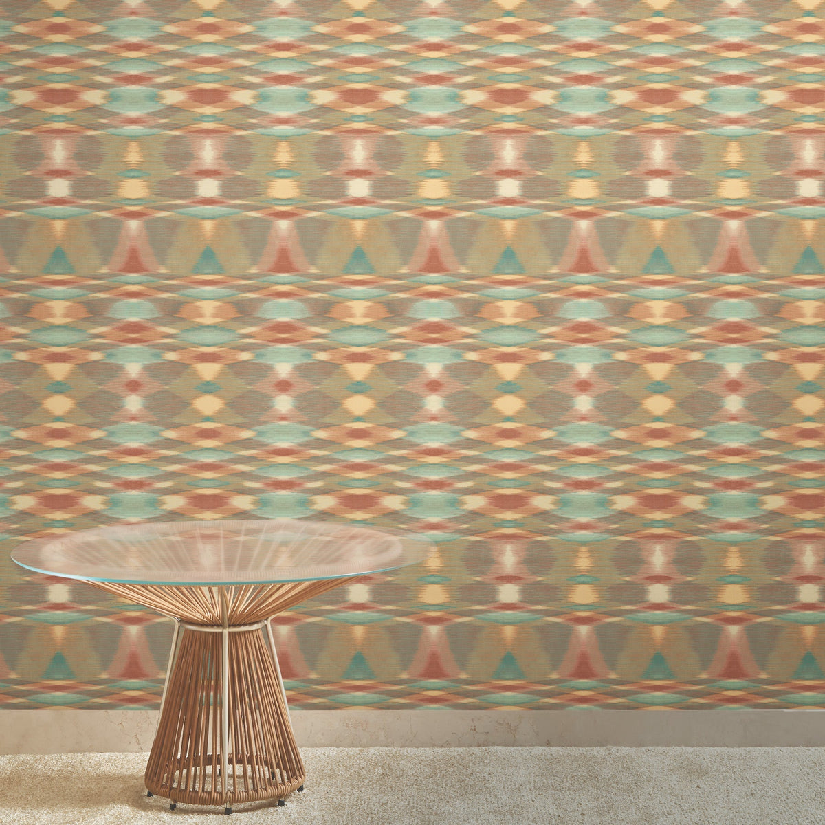 A round, glass-topped table with a wire base stands on a beige carpet in front of the York Wallcoverings Sunrise Flame Wallpaper.
