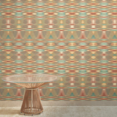 A round, glass-topped table with a wire base stands on a beige carpet in front of the York Wallcoverings Sunrise Flame Wallpaper.