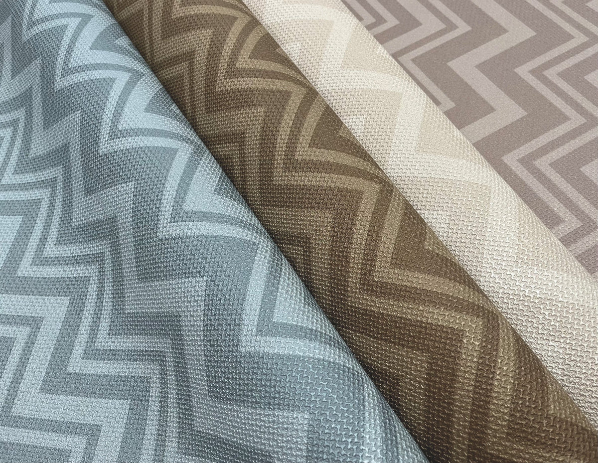 Four rolls of York Wallcoverings Iconic Shades Wallpaper featuring a textured zigzag pattern in blue, brown, beige, and taupe are laid side by side, showcasing their colors and designs.