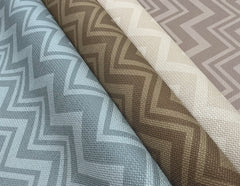 Four rolls of Iconic Shades Wallpaper by York Wallcoverings—featuring textured finishes with zigzag geometric patterns in blue, brown, beige, and taupe—are arranged side by side to showcase their distinct hues and modern designs.