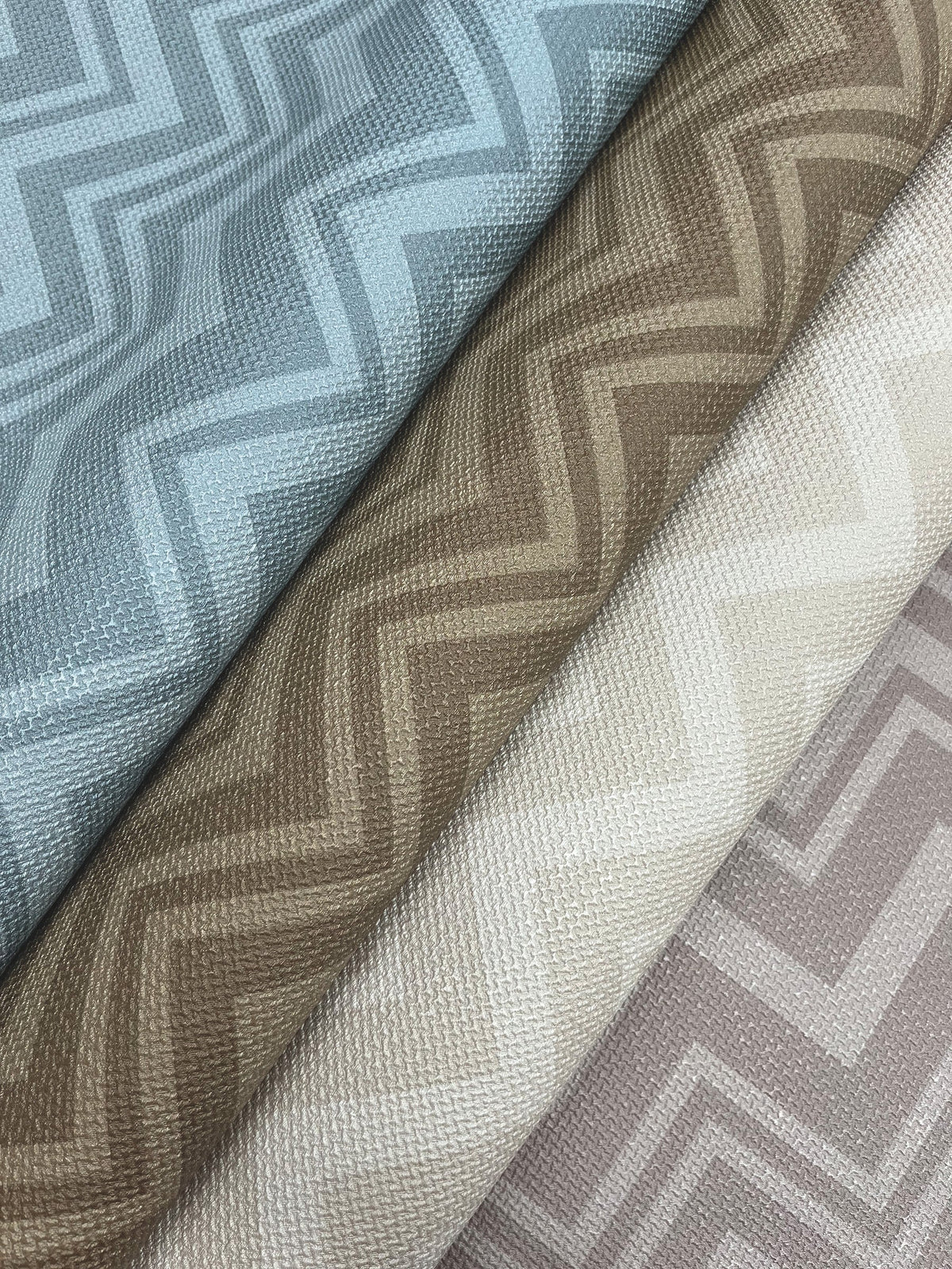 Three variations of the Iconic Shades Wallpaper by York Wallcoverings featuring textured zigzag patterns in blue, brown, and cream are displayed side by side in a close-up view.