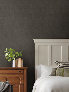 Magnolia Home Challenger Wallpaper features a fine, repeating dark gray chevron pattern behind a bedroom scene with a wooden nightstand and white headboard.