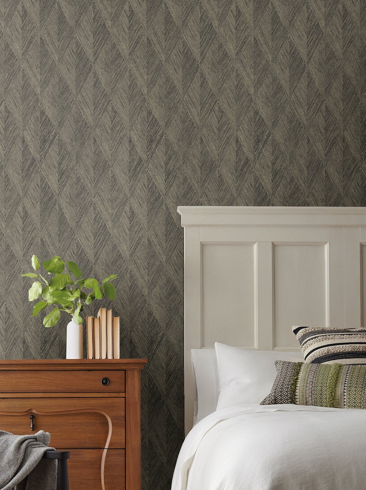 Magnolia Home Challenger Wallpaper with a dark, textured diamond pattern on a wall behind a bed and wooden nightstand.