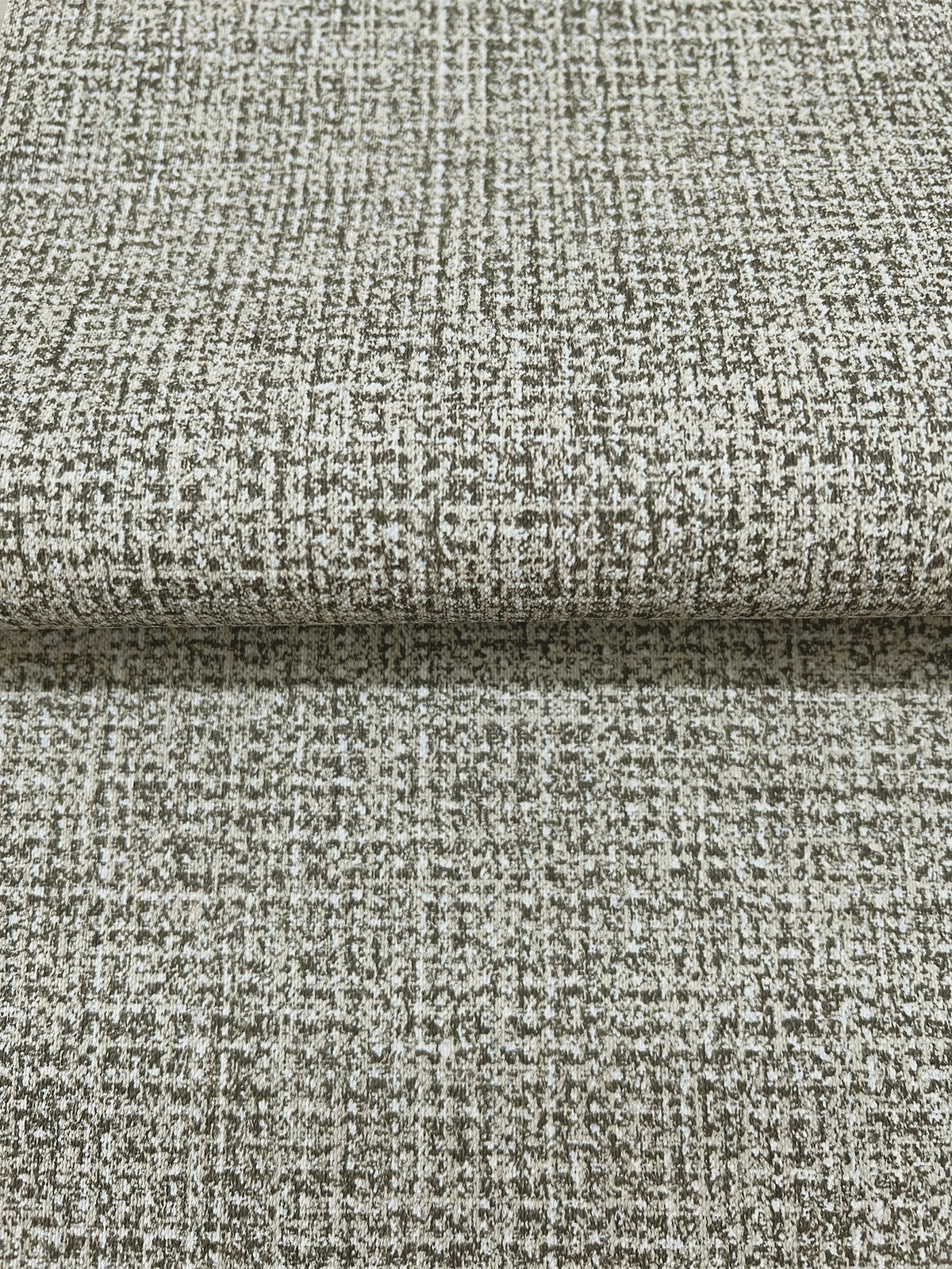 Folded sheet of Magnolia Home Brindled Wallpaper featuring a mottled, grid-like pattern in shades of brown and off-white.