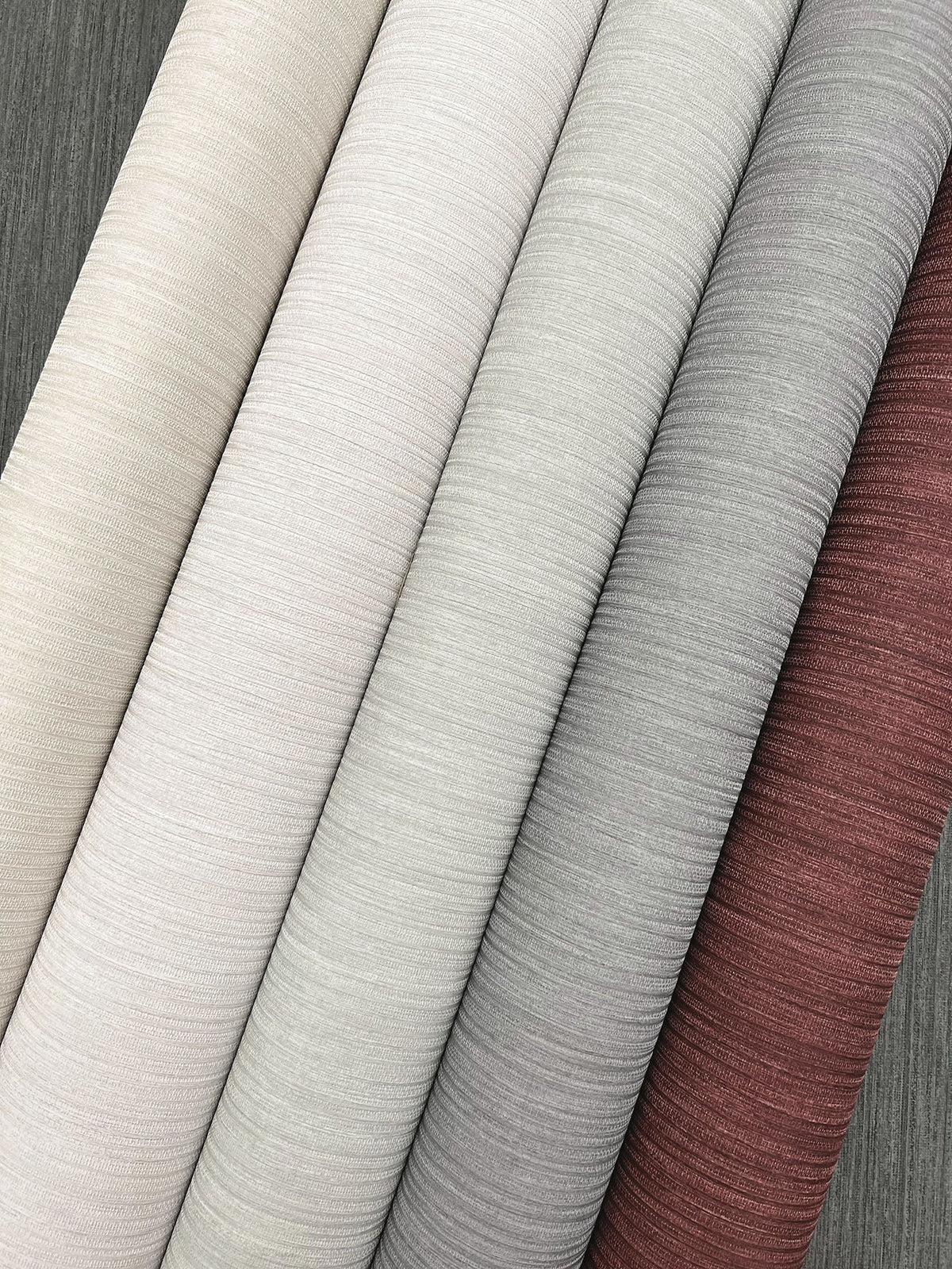 Six vertical rolls of Smooth as Silk Wallpaper in shades of cream, gray, and maroon.