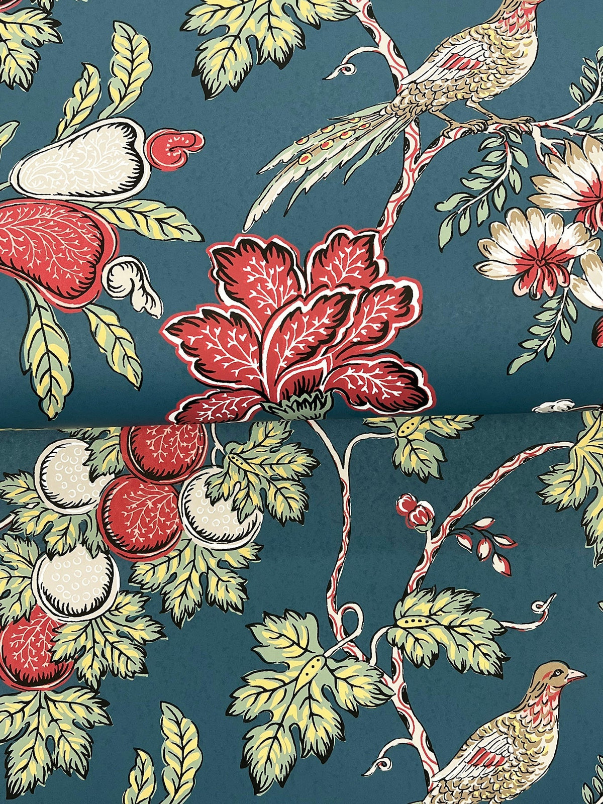 Parterre Jacobean Wallpaper by York Wallcoverings features an ornate, symmetrical design with red, white, and yellow flowers, green leaves, and two birds set against a blue background.