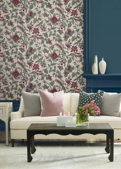Elegant living room featuring a cream sofa with pink and gray pillows, a black coffee table topped with a vase of pink tulips, York Wallcoverings Parterre Jacobean Wallpaper, blue paneled wall, and three white decorative vases displayed on a shelf.