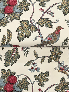 York Wallcoverings’ Parterre Jacobean Wallpaper showcases a nature-inspired pattern with birds, butterflies, leafy green branches, vibrant red and blue fruit, and delicate white berries set against a cream background.
