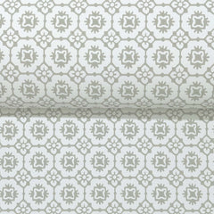 A partially unrolled roll of York Wallcoverings’ Priti Floral Grid Wallpaper displays its repeating geometric floral pattern in light gray and white tones.