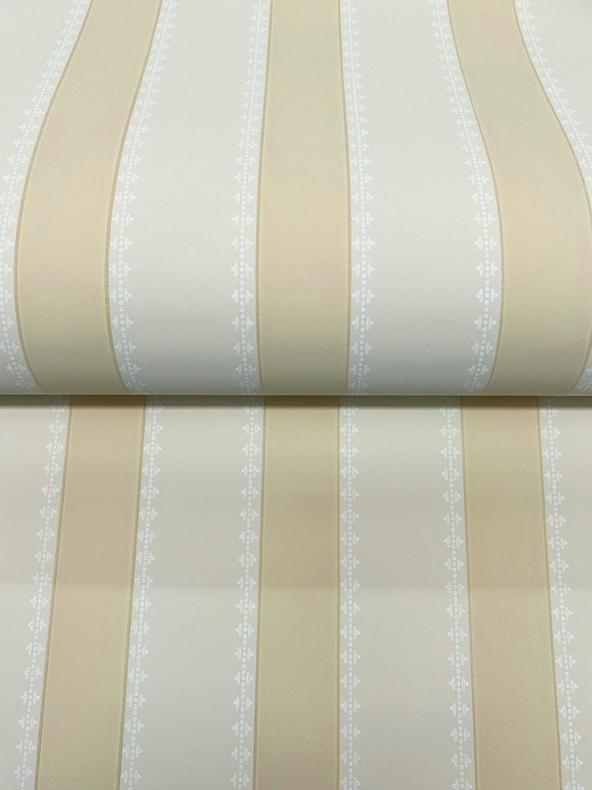 The Tilford Awning Stripe Wallpaper by York Wallcoverings features beige and cream vertical stripes accented with delicate white decorative patterns along the edges.
