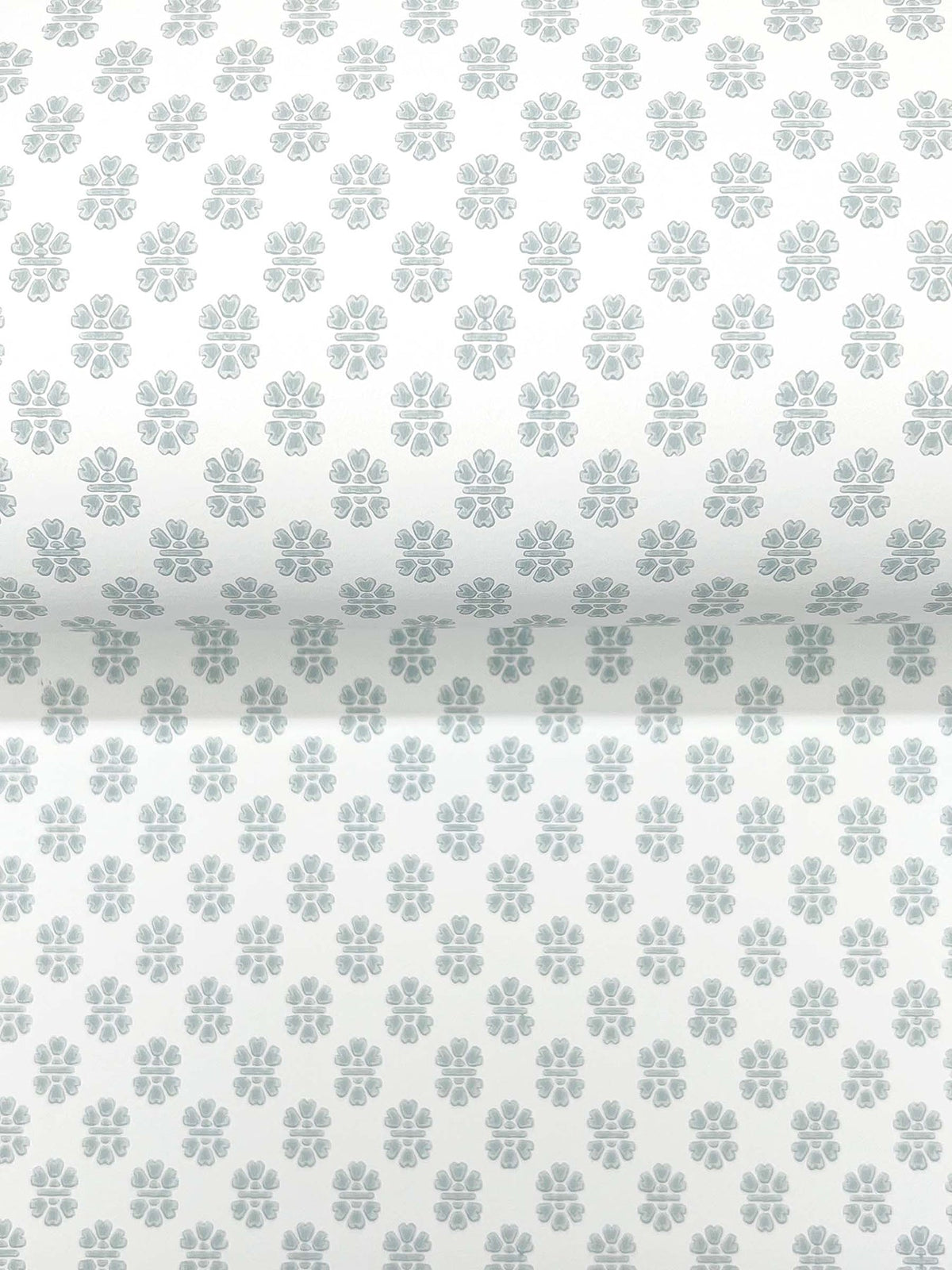 The Brioni Floral Stamp Wallpaper by York Wallcoverings features a roll of white wallpaper adorned with a repeating pattern of small, light gray, four-petal floral shapes.