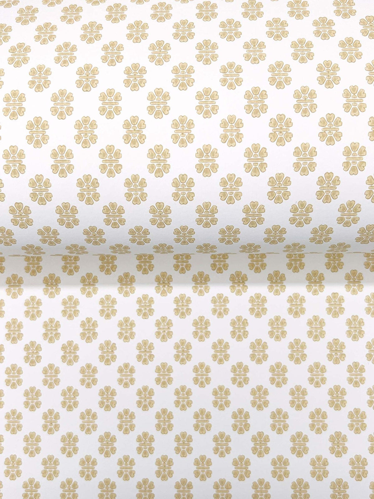 A close-up of Brioni Floral Stamp Wallpaper by York Wallcoverings, featuring a rolled view that reveals both the front and inner sides. The wallpaper displays a beige floral pattern with rows of small, evenly spaced flowers on a white background.