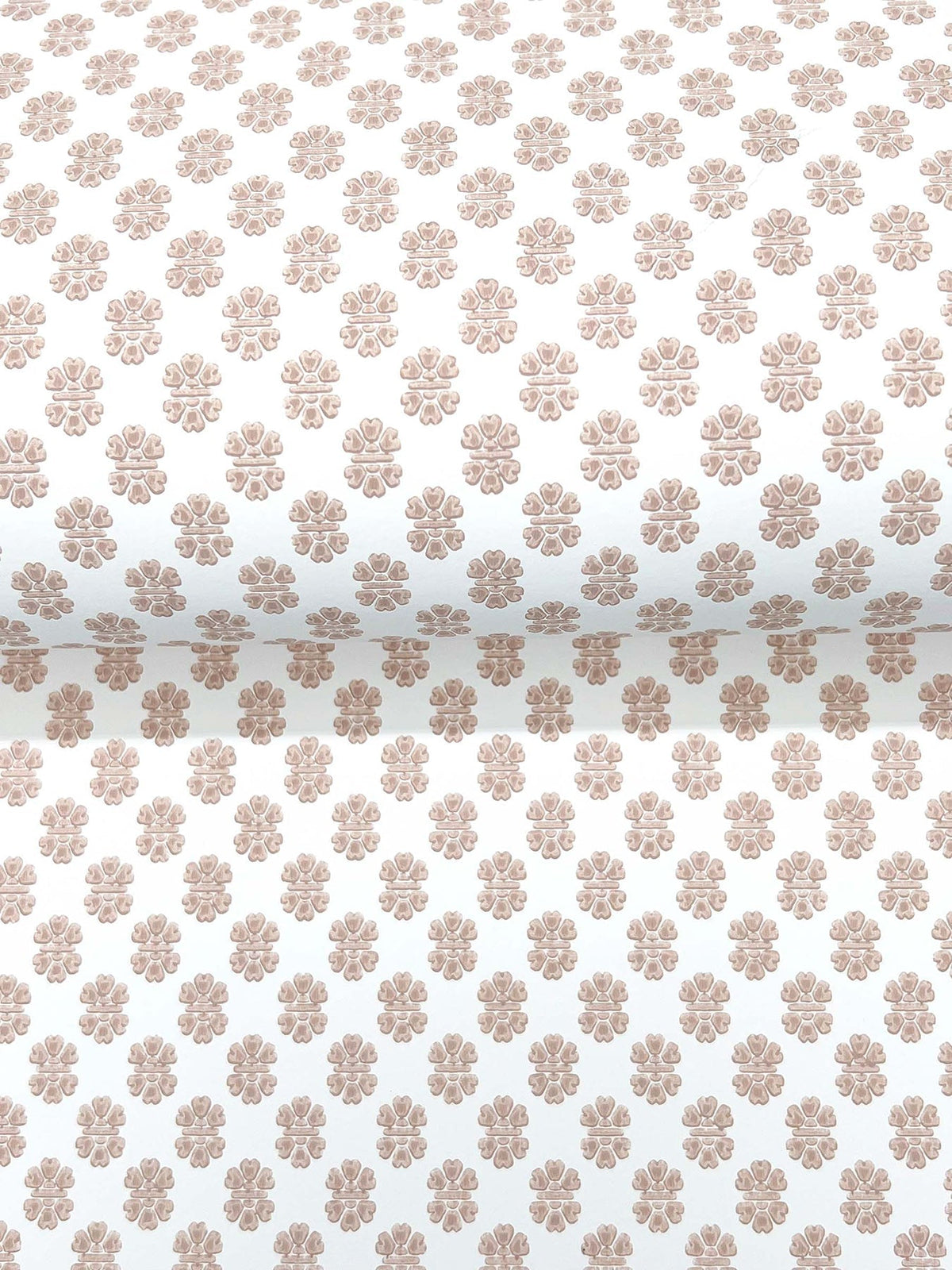 A close-up of a roll of Brioni Floral Stamp Wallpaper by York Wallcoverings, featuring a neatly aligned and evenly spaced pattern of small, light brown floral designs on a white background.